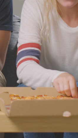 Vertical-Video-Close-Up-Of-Friends-At-Home-Sharing-Eating-Takeaway-Pizza-Delivery